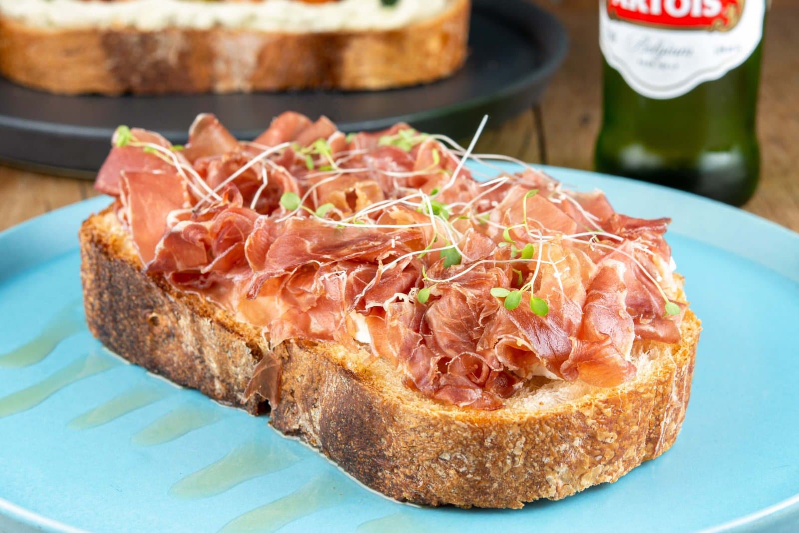Tartine com presunto cru e brotos em prato azul